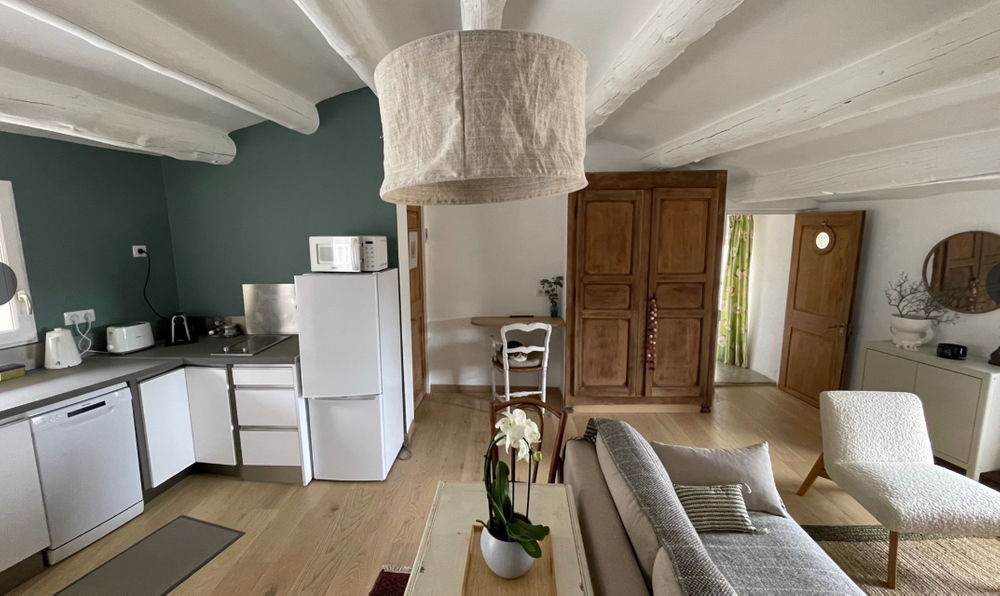 Heller Wohnbereich und voll ausgestattete Küche von La Cigale in Vaugines, mit sichtbaren Balken und warmer Dekoration