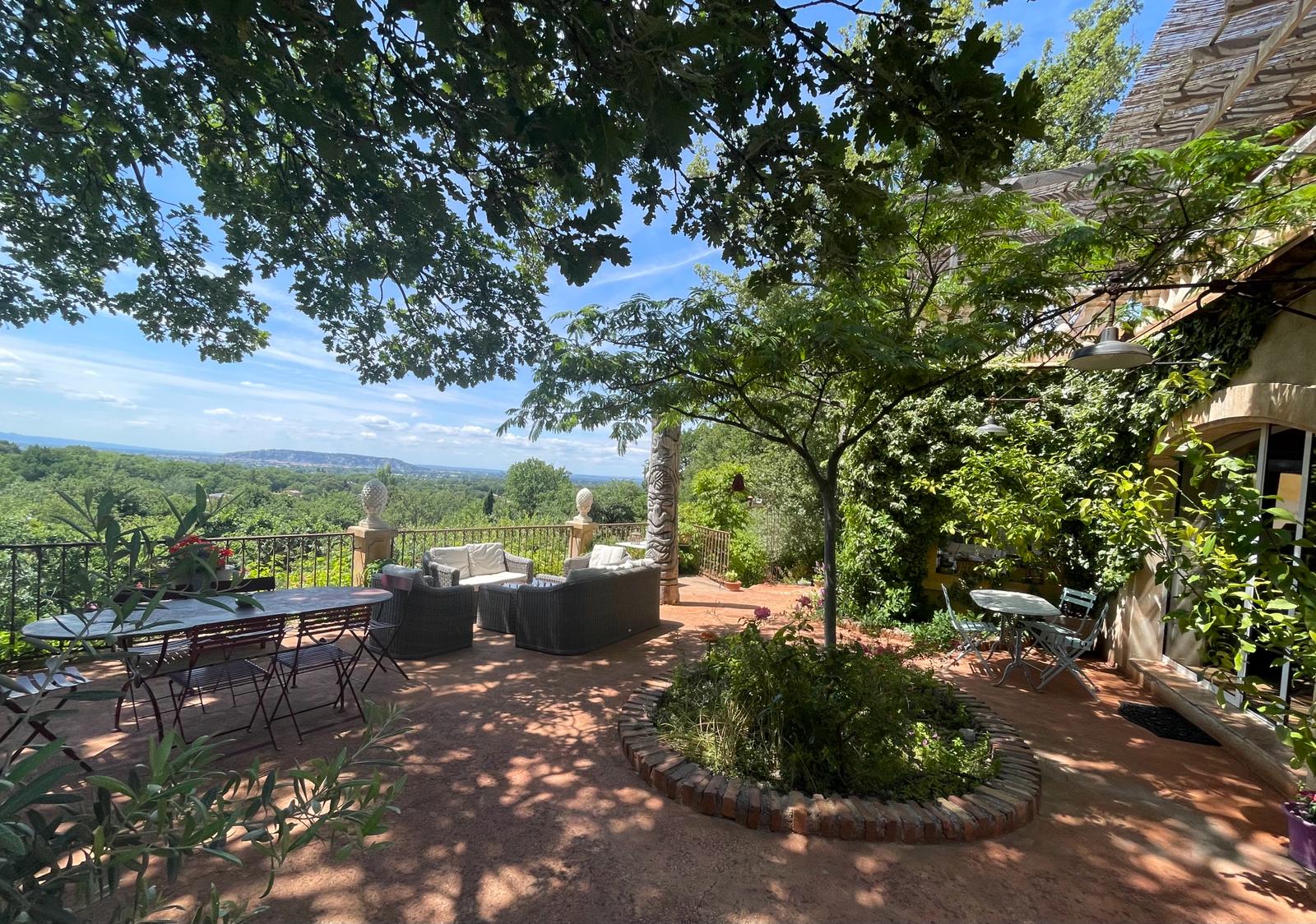 Schattige Terrasse des Domaine Les Félibrés mit Panoramablick auf den Luberon und gemütlichem Entspannungsbereich.