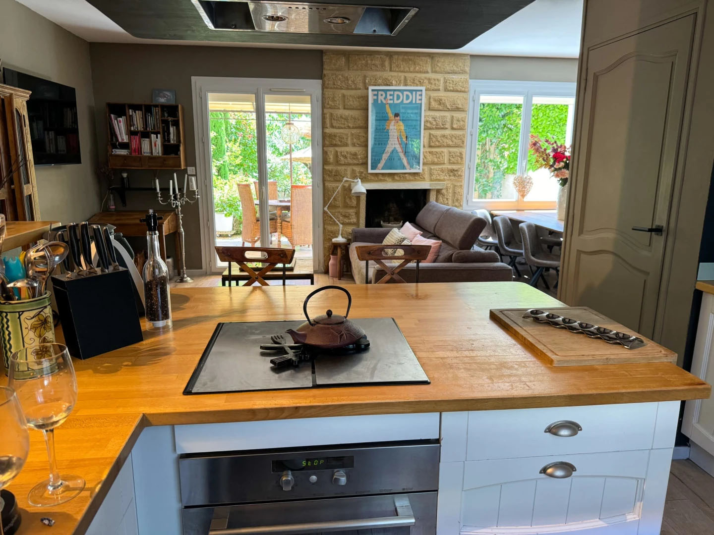 Blick auf eine moderne und gemütliche Küche, die in das Wohnzimmer übergeht, mit direktem Zugang zur grünen Terrasse des Nid d'Ange en Provence.