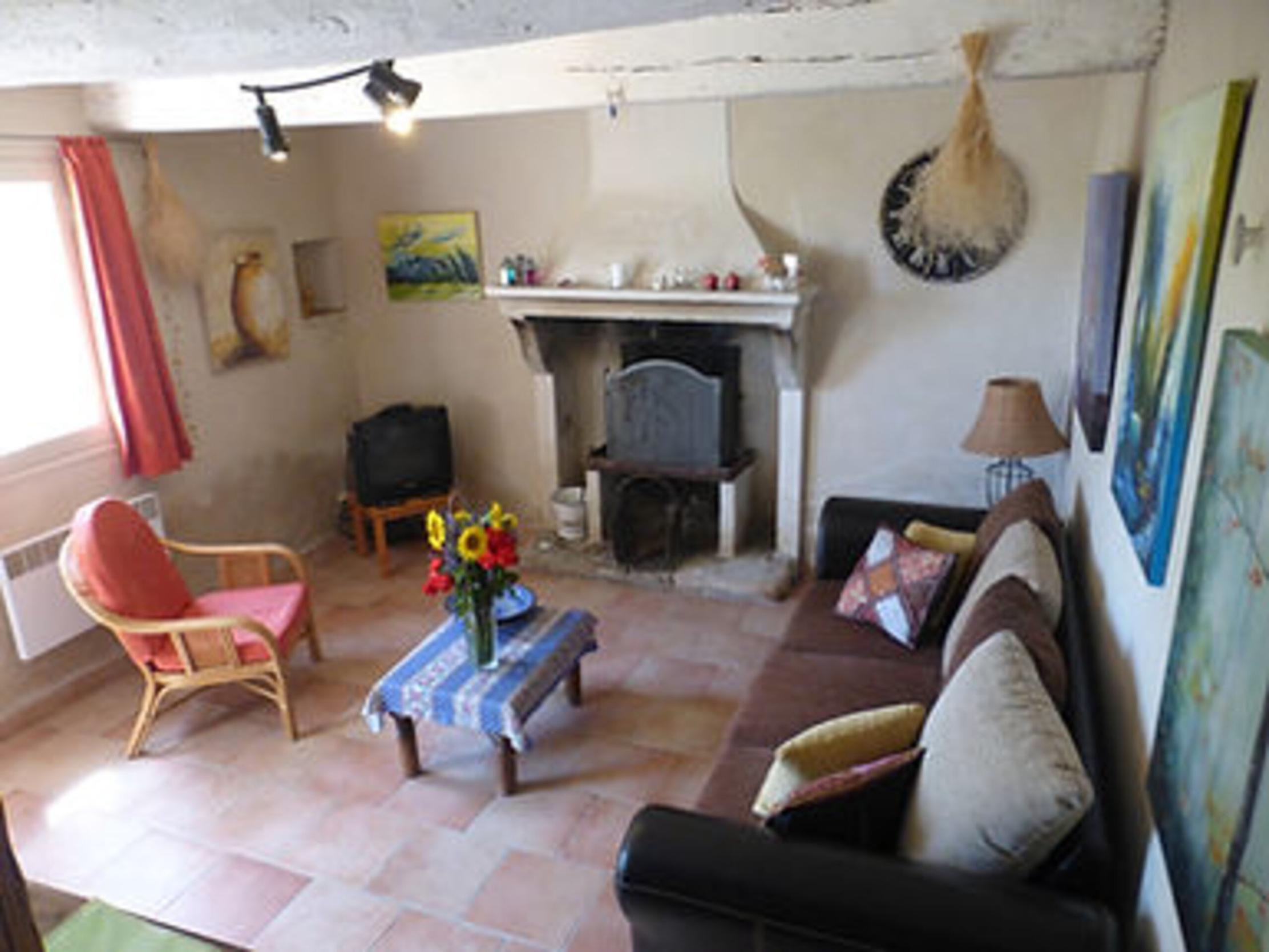 Wohnzimmer des Gîte Rosalie mit altem Kamin, Sofa und provenzalischer Dekoration