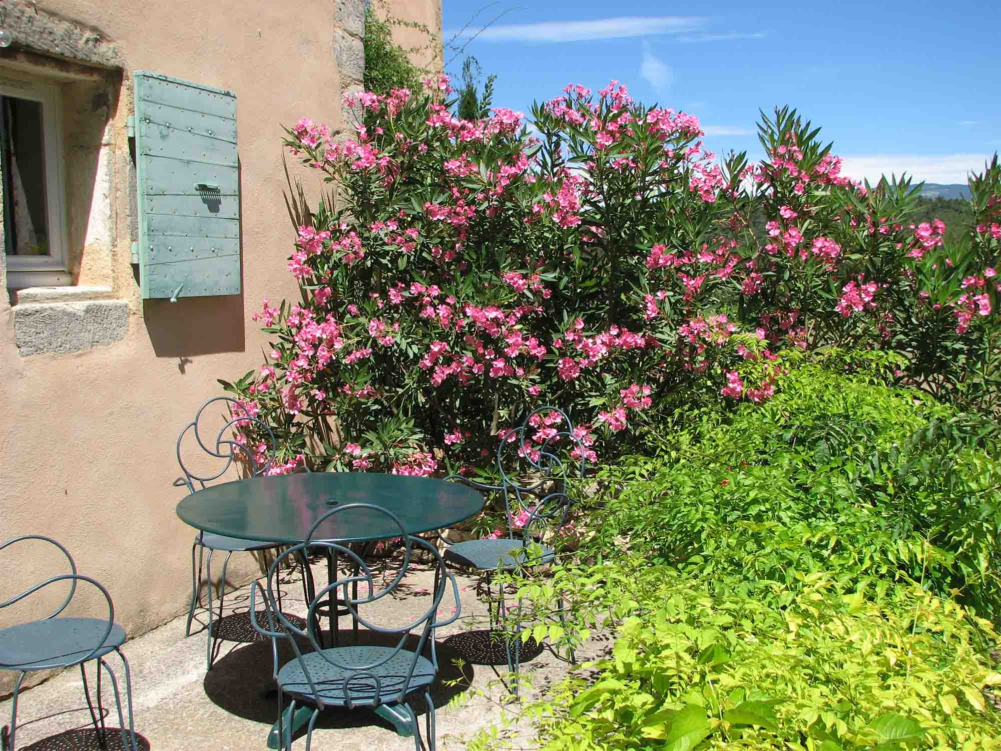 Private Terrasse der Maison de Rosalie mit Gartenmöbeln aus Schmiedeeisen und Blumen
