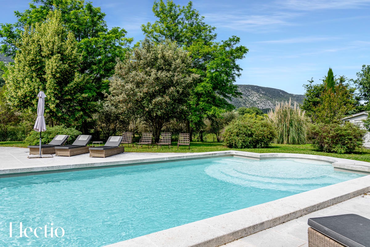 Beheizter Pool der Résidence Les Petitons in Oppède-le-Vieux, umgeben von Liegestühlen und Natur mit Blick auf die Hügel des Luberon