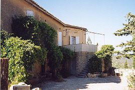 Fassade und Terrasse des Moulin de Bel Air in Gordes, umgeben von Grün