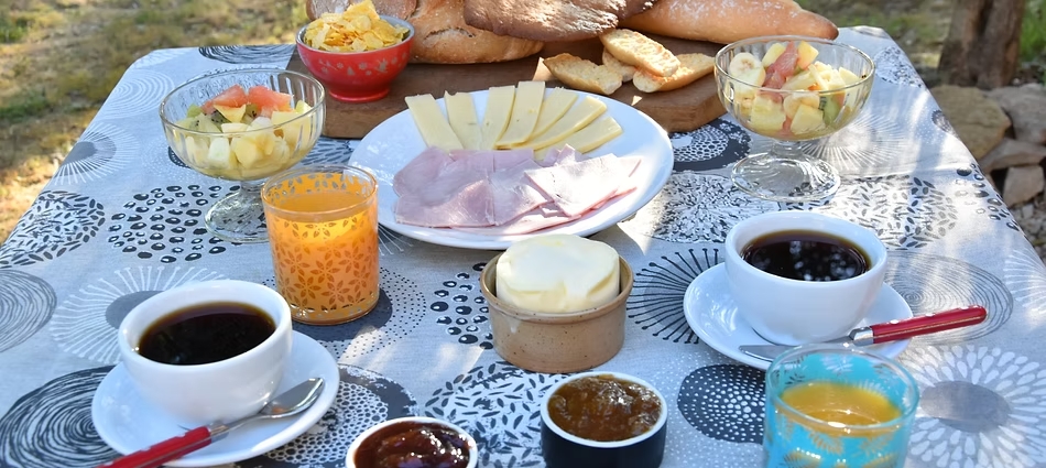Hausgemachtes Frühstück im Freien mit Heißgetränken, Obst, Käse und Marmeladen