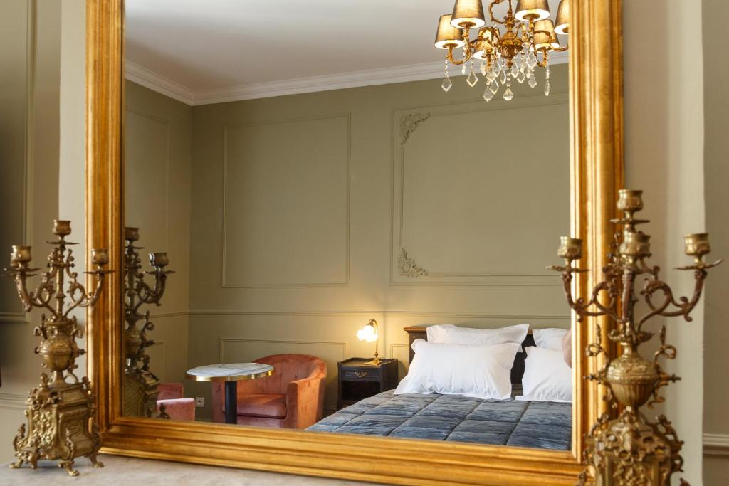 Spiegelbild eines Doppelbetts in einem goldenen Spiegel – helle und elegante Suite