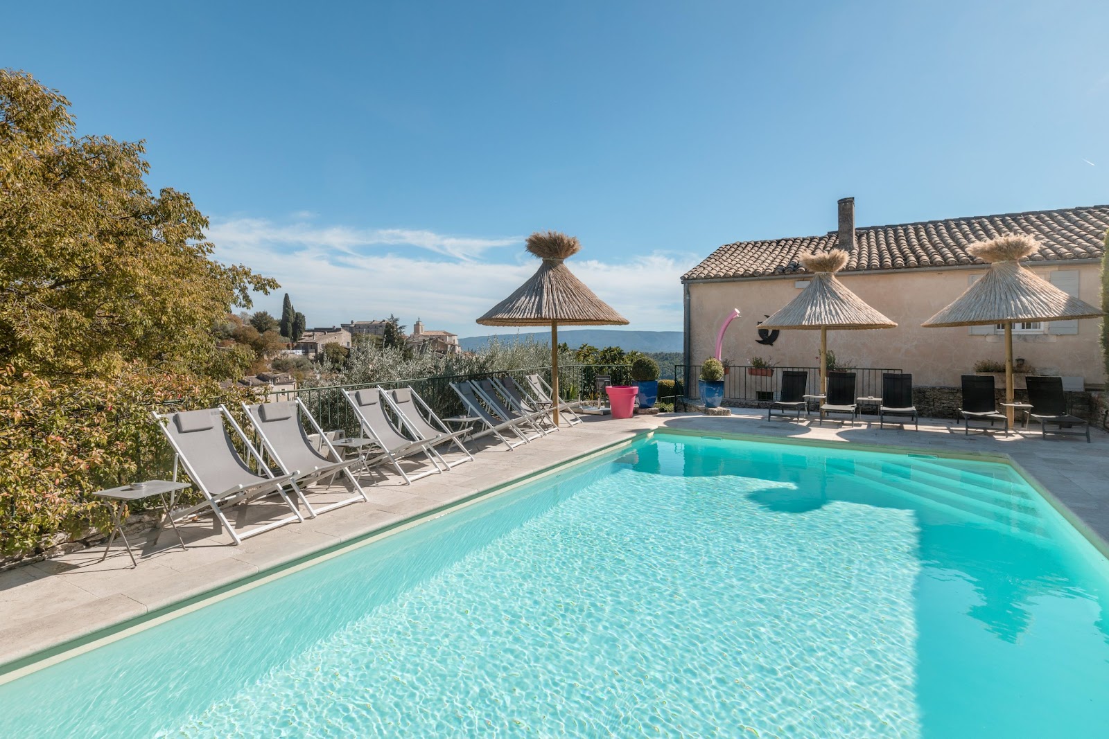 Außenpool des Hotels Le Mas des Romarins in Gordes mit Sonnenliegen und freiem Blick auf den Luberon