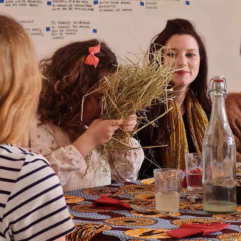Gemeinsamer Moment rund um eine Mahlzeit während der Performance Auf Stroh, ein Bankett, die Theater, Küche und Beteiligung der Bewohner verbindet.