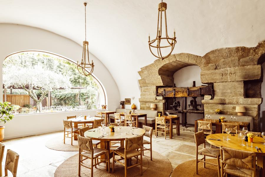 Speisesaal des Restaurants Bacheto in Lourmarin mit gedeckten Tischen und historischem Steinkamin