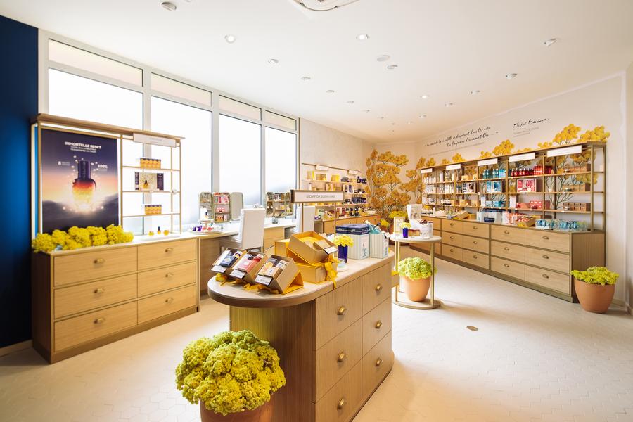 Helles Interieur der L'Occitane en Provence Boutique, in der die charakteristischen Kosmetik- und Duftprodukte der Marke präsentiert werden.