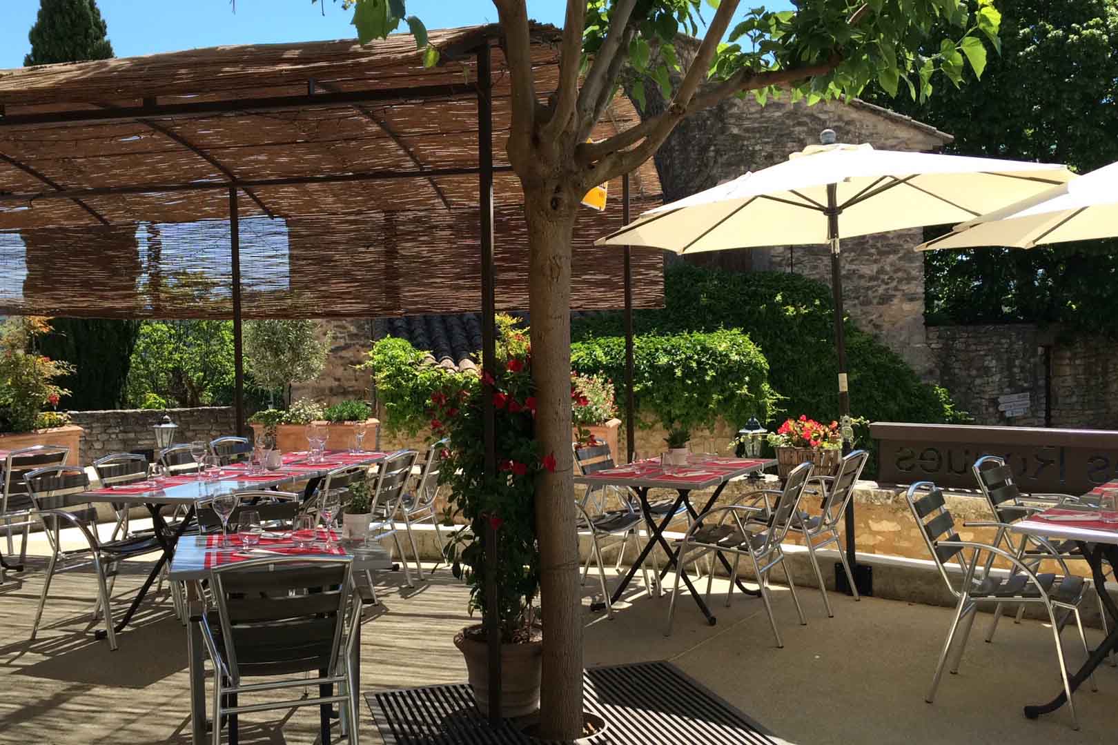Schattige Terrasse des Bistrot des Roques in Saint-Pantaléon mit Tischen im Herzen des Luberon
