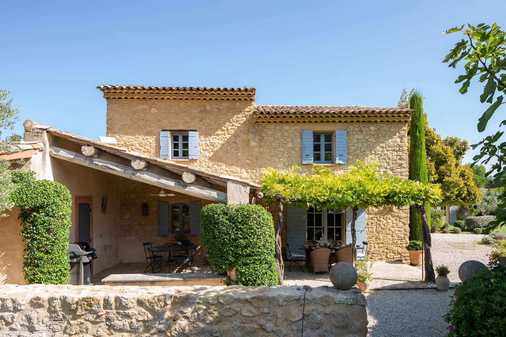 Mas Petit Collongue in Lourmarin – Fassade des provenzalischen Landhauses mit schattiger Terrasse Steinfassade des Mas Petit Collongue in Lourmarin mit schattiger Terrasse und Garten