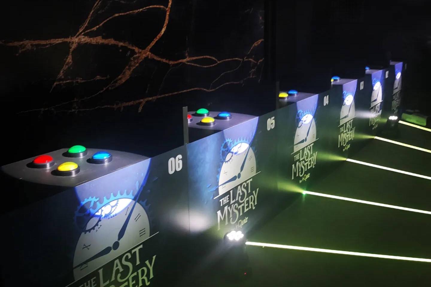 Quiz-Game-Set bei The Last Mystery mit nummerierten Pulten und bunten Buzzern im TV-Stil