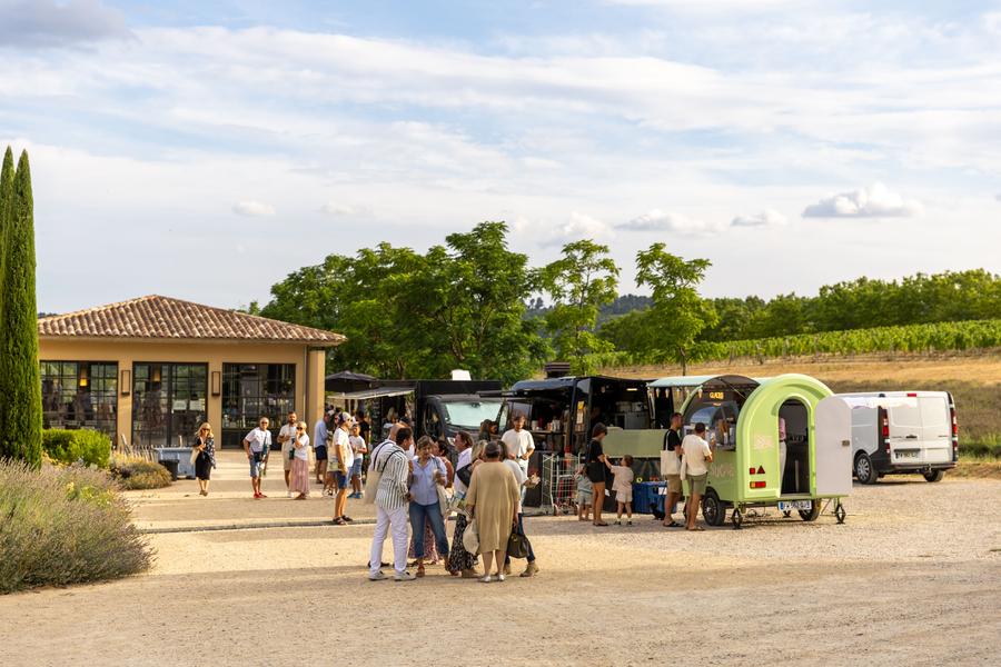 Foodtrucks und Besucher im Park des Château de Sannes während des Festivals Passions en Luberon