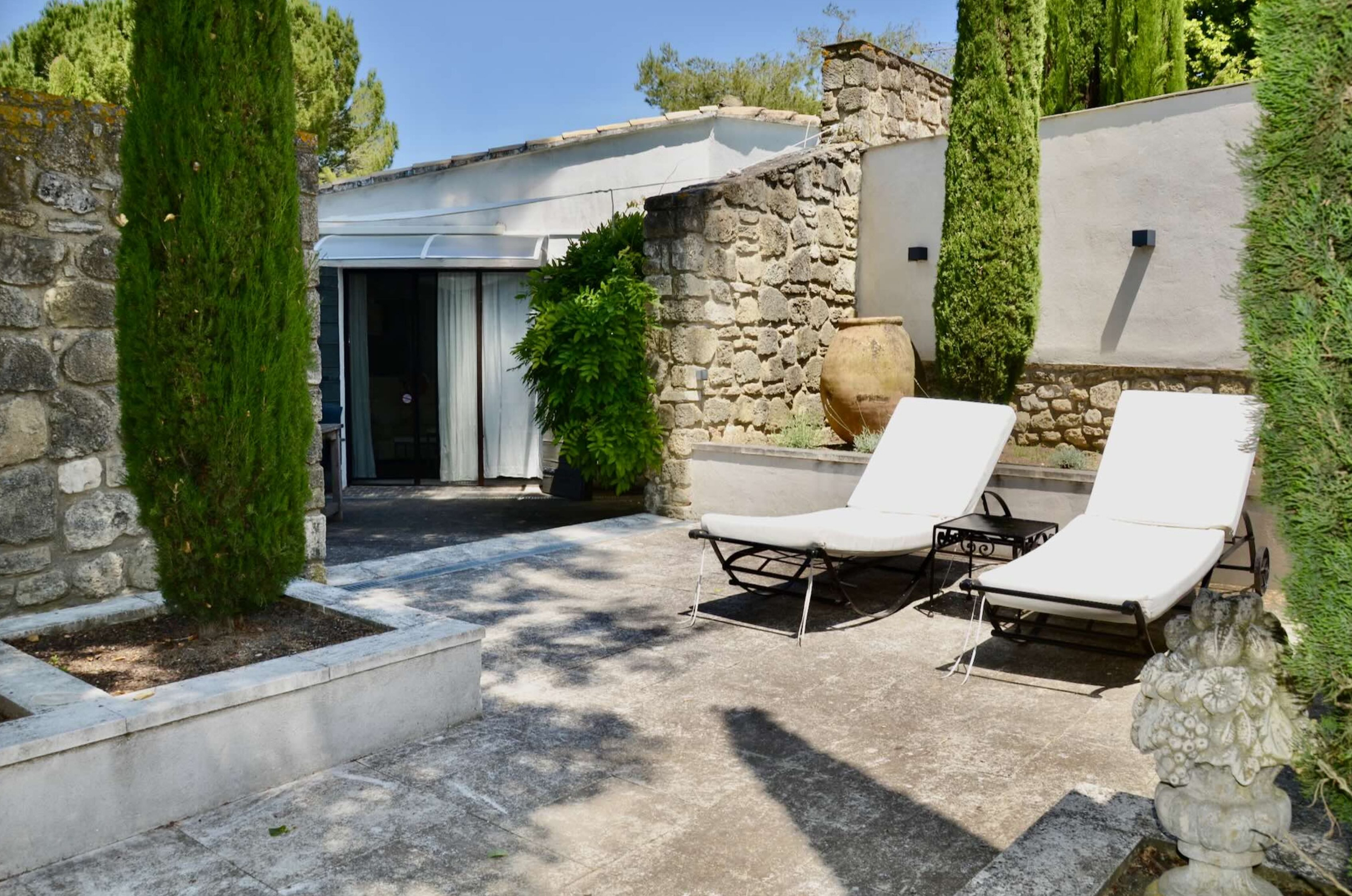 Außenbereich mit Sonnenliegen und Zypressen im Garten des Hauses Les Oliviers in Oppède im Luberon