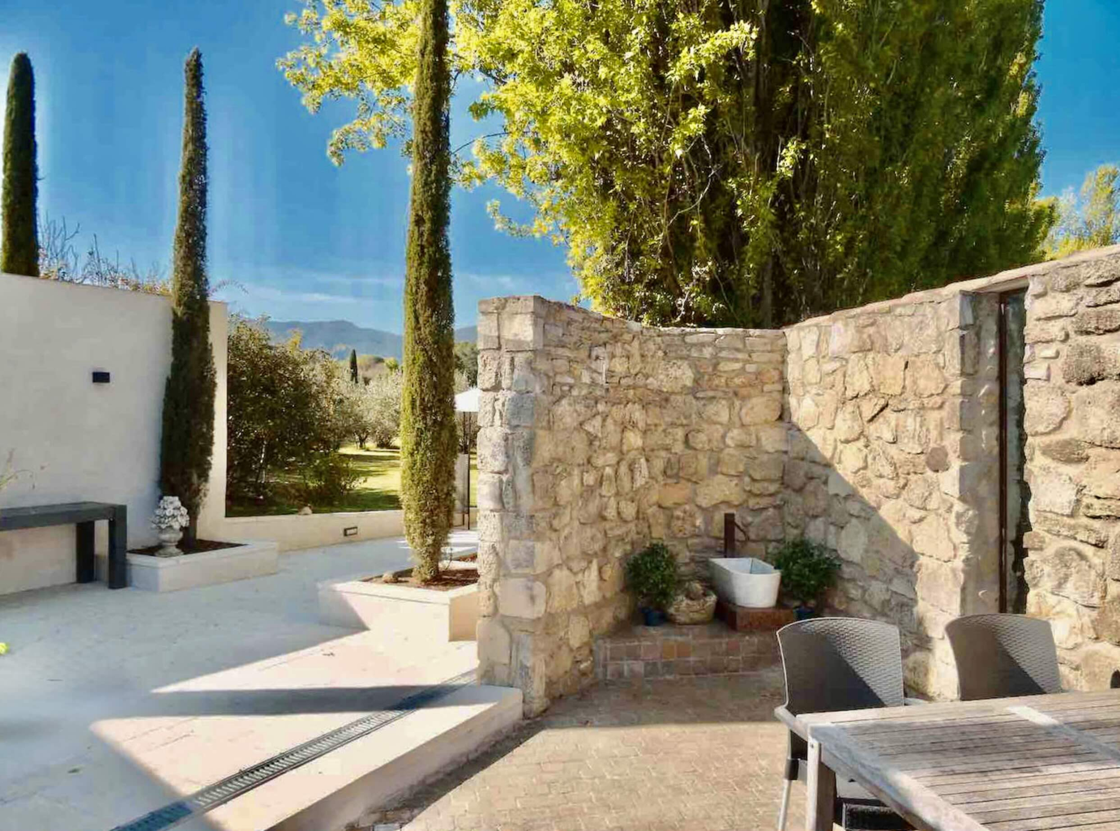 Private Terrasse des Hauses Les Oliviers in Oppède mit Steinmauern, Zypressen und Ruhebereichen in einer friedlichen Luberon-Umgebung