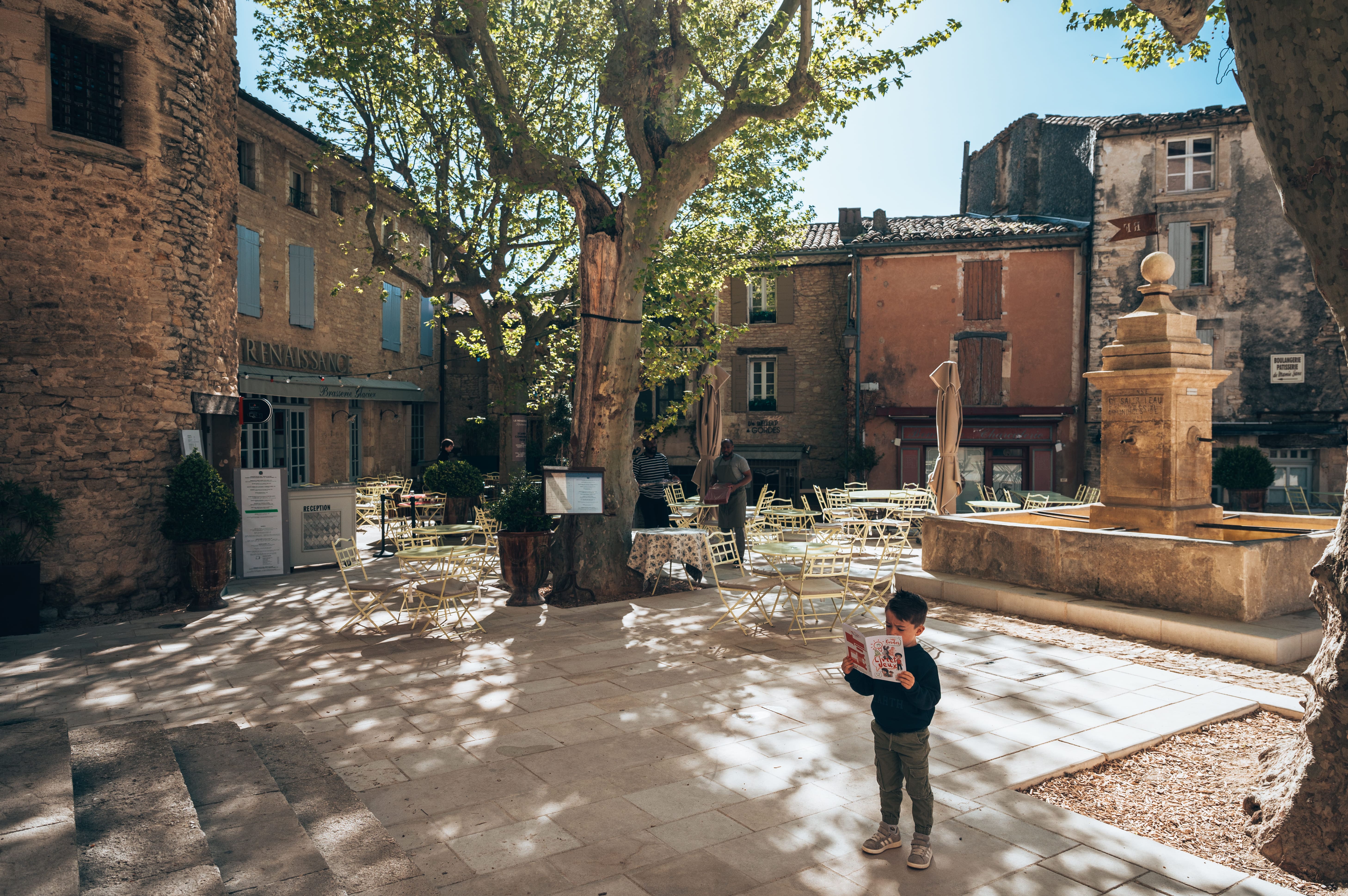 Kinder erkunden mit einem Spielheft ein Dorf im Luberon und suchen in den Straßen nach Hinweisen
