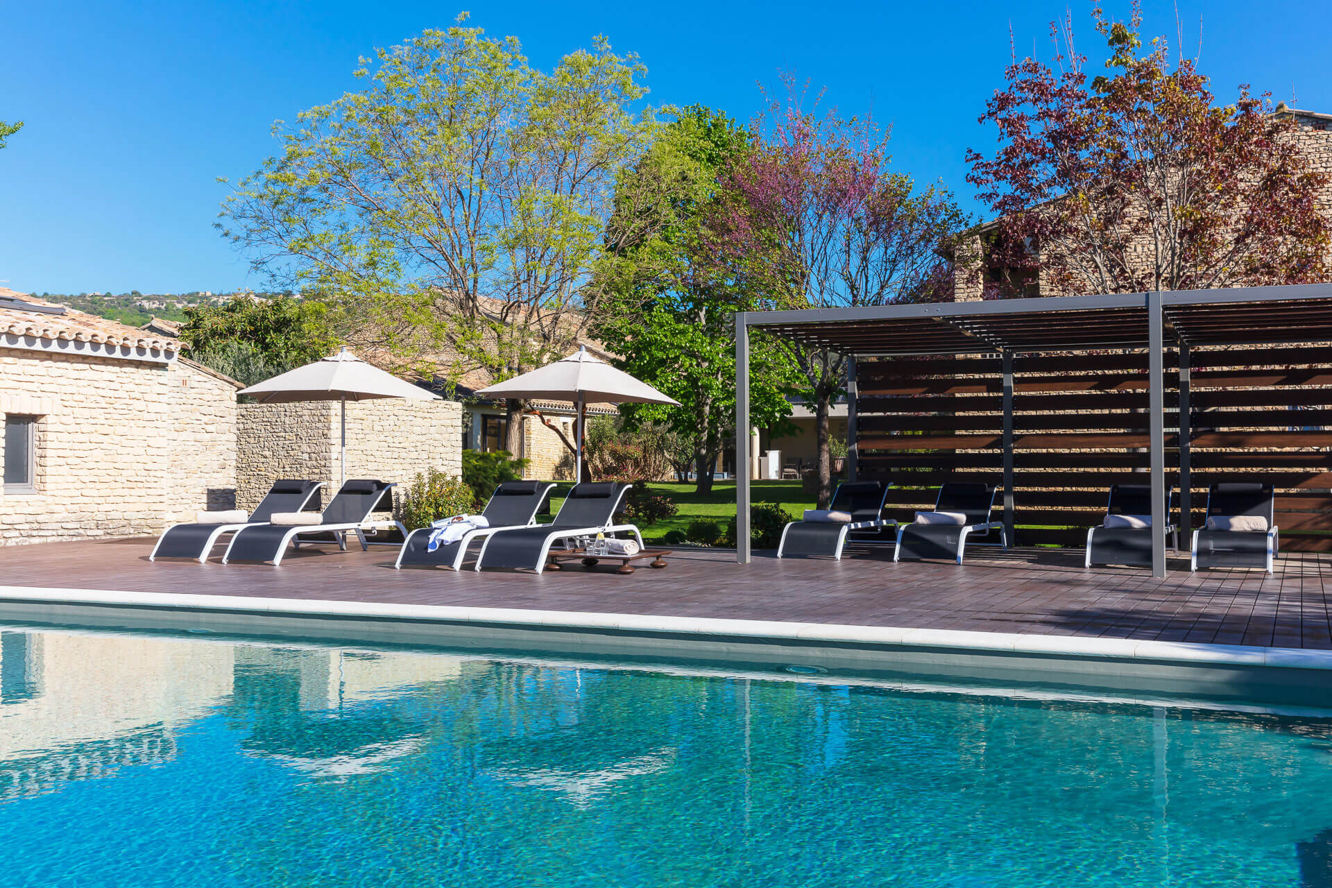 Außenpool des Hotel Carcarille in Gordes mit Liegestühlen und Gartenanlage