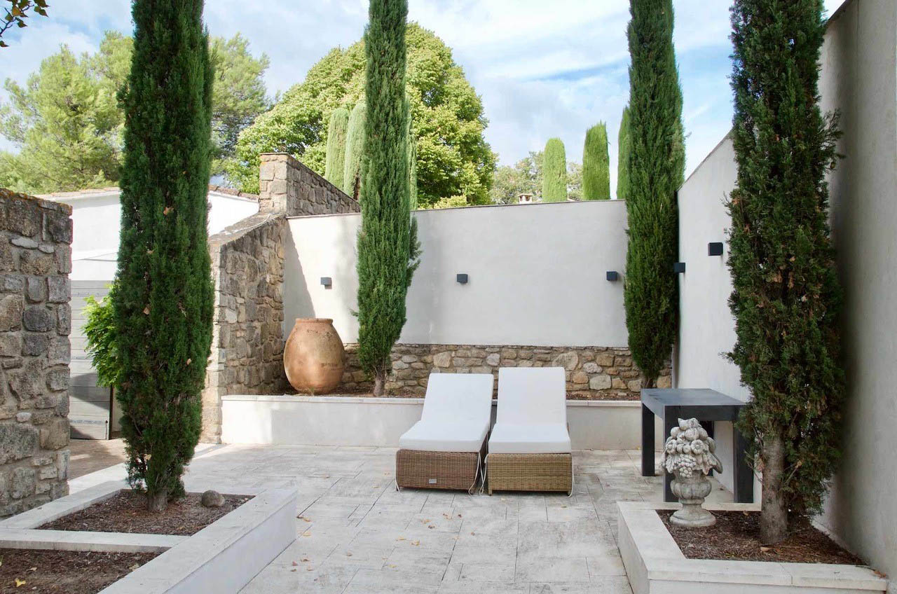 Außenbereich mit Sonnenliegen, Haus Les Oliviers in Oppède Außenbereich mit Sonnenliegen und Zypressen im Garten des Hauses Les Oliviers in Oppède im Luberon