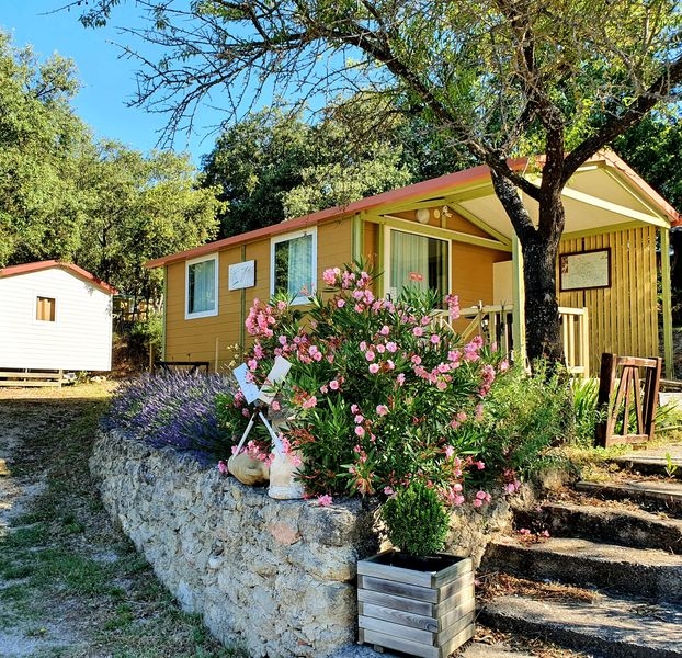 Farbenfrohes und einladendes Chalet auf dem Camping Le Moulin à Vent, umgeben von Grün und Blumen
