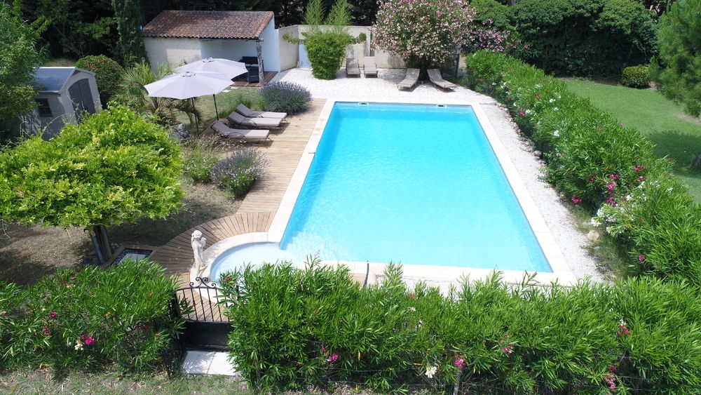 Außenpool mit Sonnenliegen, Sonnenschirmen und üppigen Gärten im Mas Séraphin, das eine entspannende Atmosphäre in L'Isle sur la Sorgue bietet