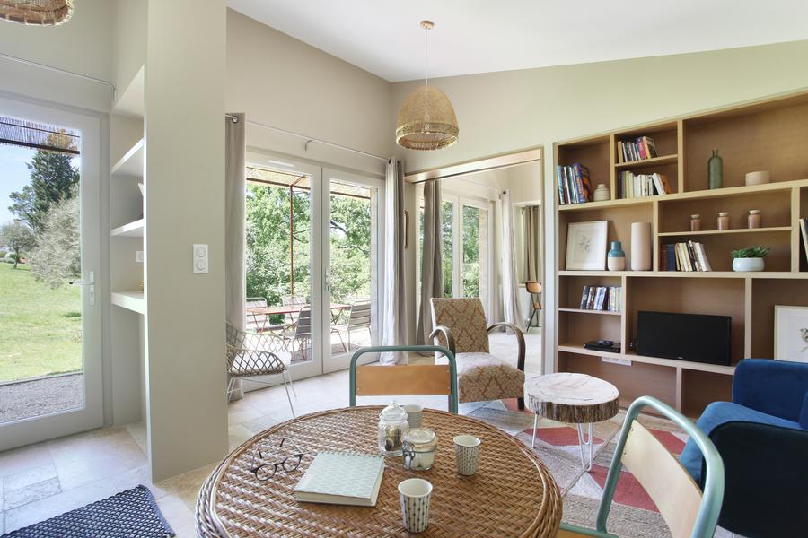 Helles Wohnzimmer des Gîte Senecio im Domaine Les Petites Vaines, ein einladender Raum mit Bibliothek und Essbereich