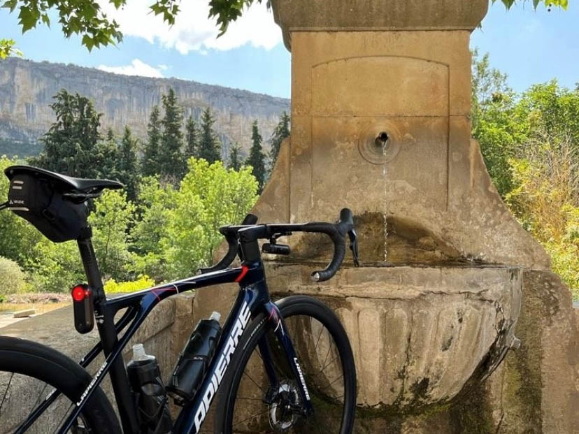 Rastpause mit dem Fahrrad auf den Straßen des Luberon, nahe einem Brunnen vor provenzalischer Landschaft