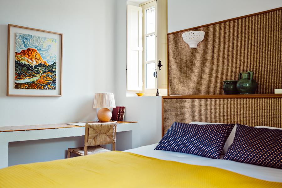 Zimmerdetail im Le Moulin in Lourmarin mit Kopfteil aus Naturfasern und komfortabler Bettwäsche