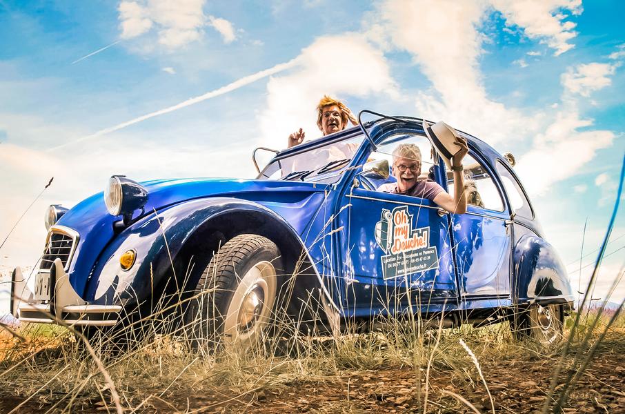 Erleben Sie das Abenteuer in einer Citroën 2CV mit Oh My Deuche im Herzen der provenzalischen Landschaften Teilnehmer genießen eine Ausfahrt in einer blauen Citroën 2CV durch die Landschaften der Provence mit Oh My Deuche