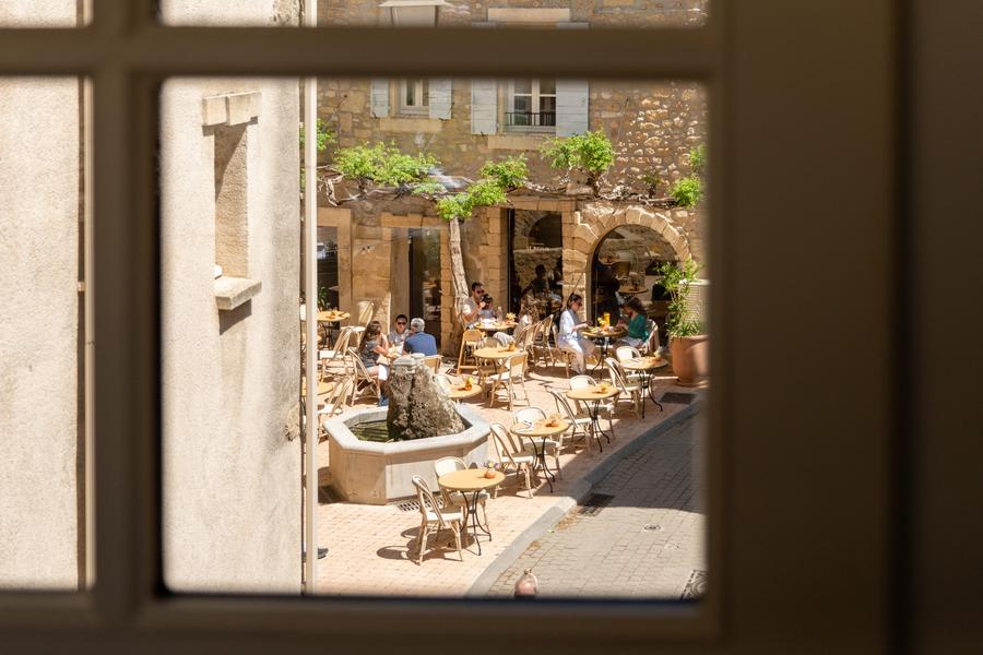 Außenterrasse des Restaurants Bacheto in Lourmarin mit Tischen rund um einen Brunnen